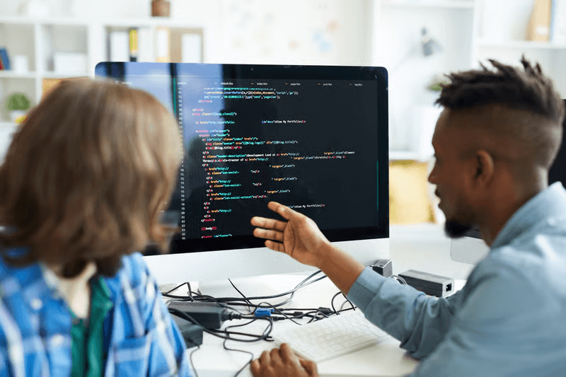 Engineering colleagues collaborating and reviewing architecture on monitor