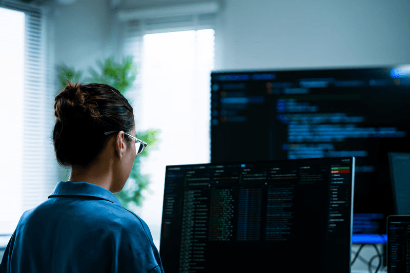 Software engineer analyzing API code on dual monitors