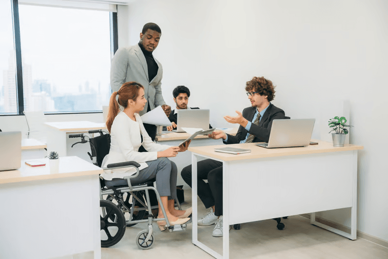 Colleagues working around a table with laptops in an accessible office