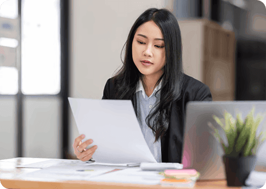 Professional reading document at desk near laptop