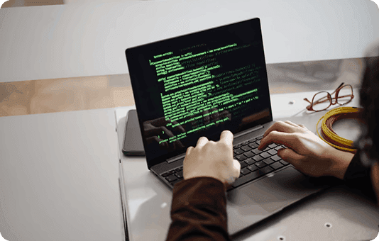 Person coding on a laptop with green terminal output