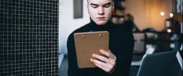 Person reading notes on a clipboard