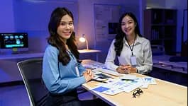 Two analysts smiling at a desk with printed charts
