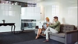 Two colleagues talking on a sofa in a bright office